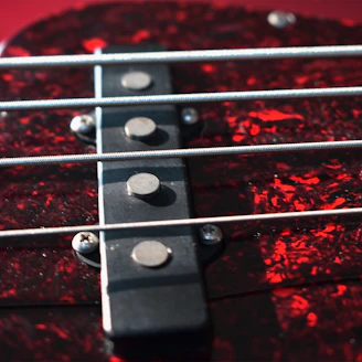 Close-up of a bass guitar with a bright, patterned pickguard attached.