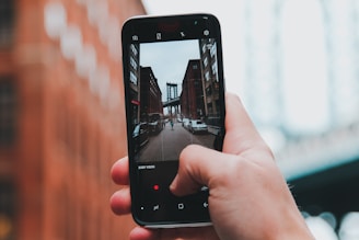 A person holding a smartphone, reporting a pothole on a city street.