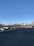 A wide, clean parking lot filled with neatly parked cars under a clear sky.