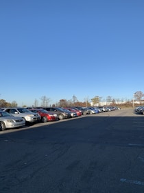 A spacious parking lot under a clear blue sky with parked vehicles in neat rows.