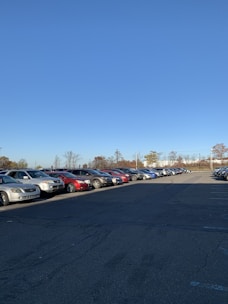 A spacious parking lot with cars neatly parked during daytime under clear skies.