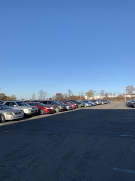 A wide, clean parking lot filled with neatly parked cars under a clear sky.