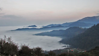 A serene, misty mountain village tucked away among lush green hills at sunrise.