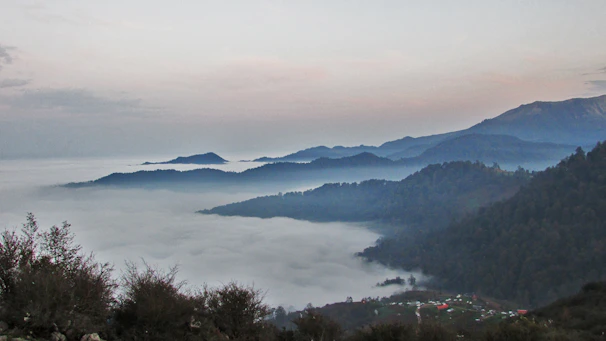 A serene, misty mountain village tucked away among lush green hills at sunrise.