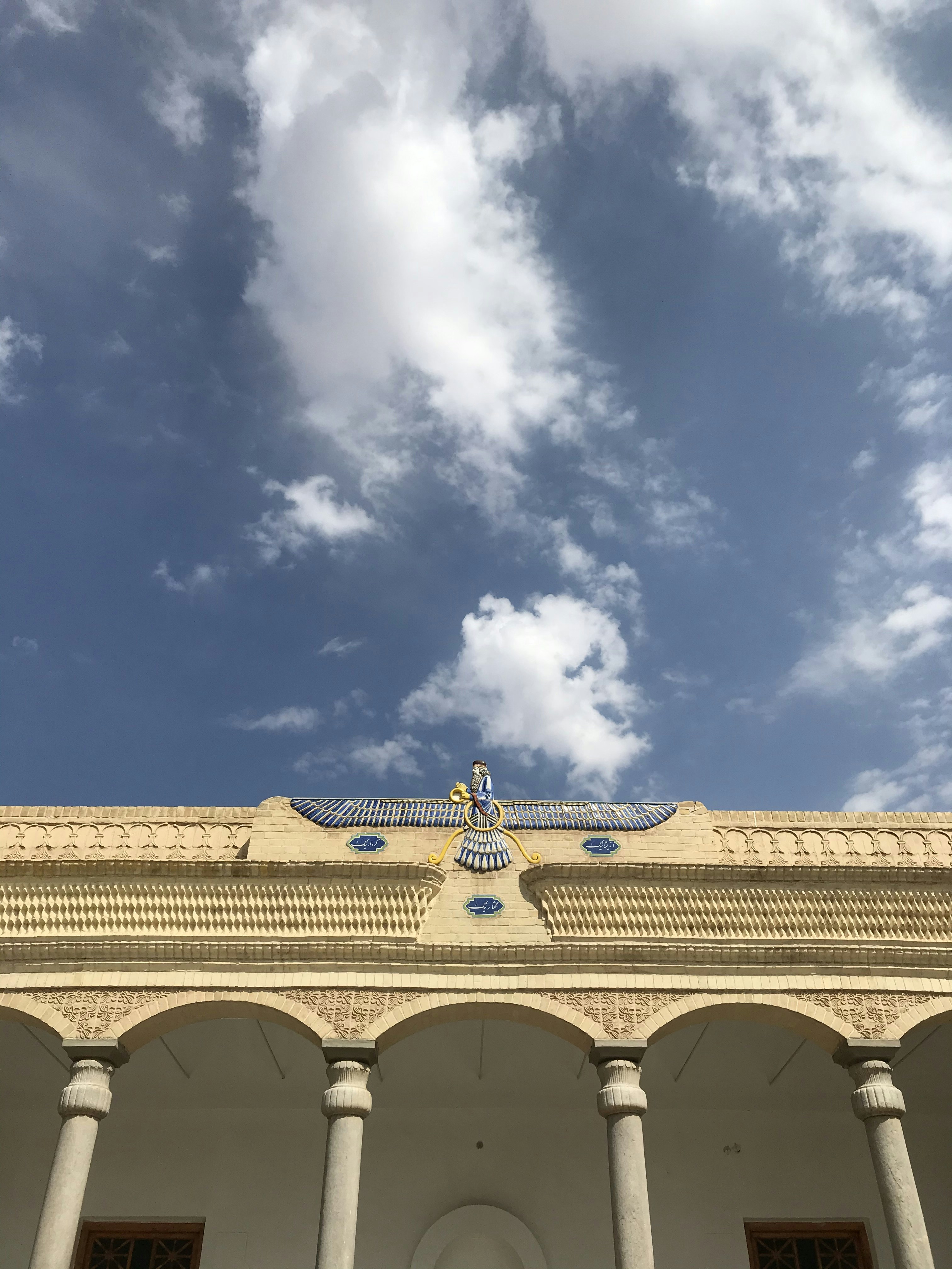 low-angle photography of white concrete building under blue and white cloudy sky