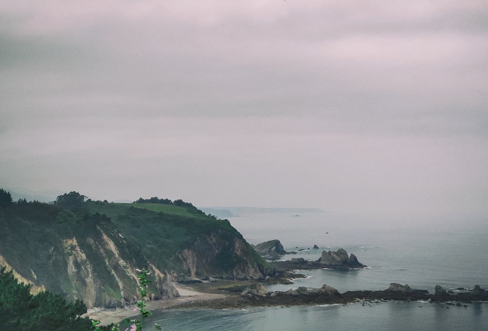 mountain by shore under gray skies