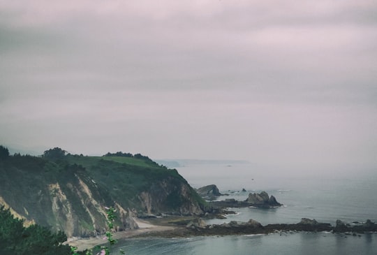 mountain by shore under gray skies in Cudillero Spain