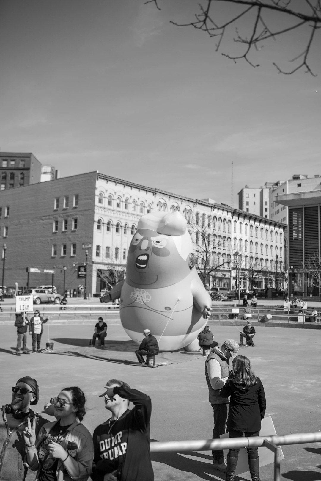 grayscale photography of people walking near large statue