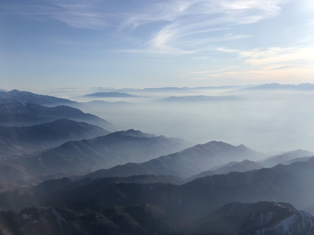 aerial photography of mountain covered with fogs under blue and white sky