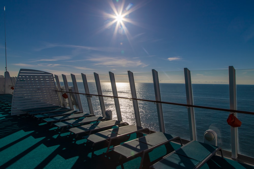 a row of chairs sitting on top of a pier next to the ocean