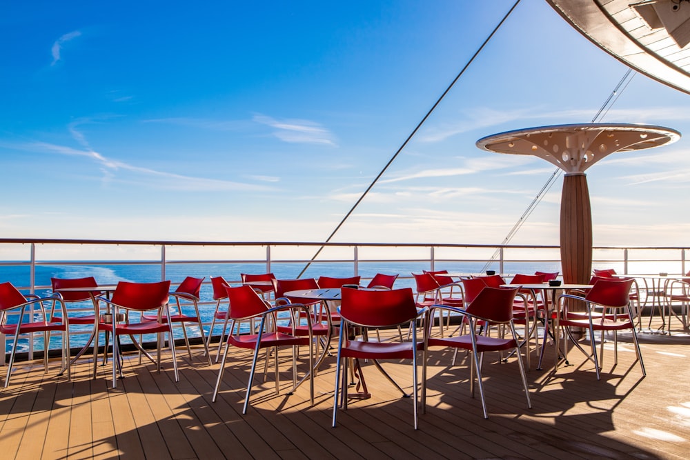 red armchairs near table viewing blue sea under blue and white sky during daytime