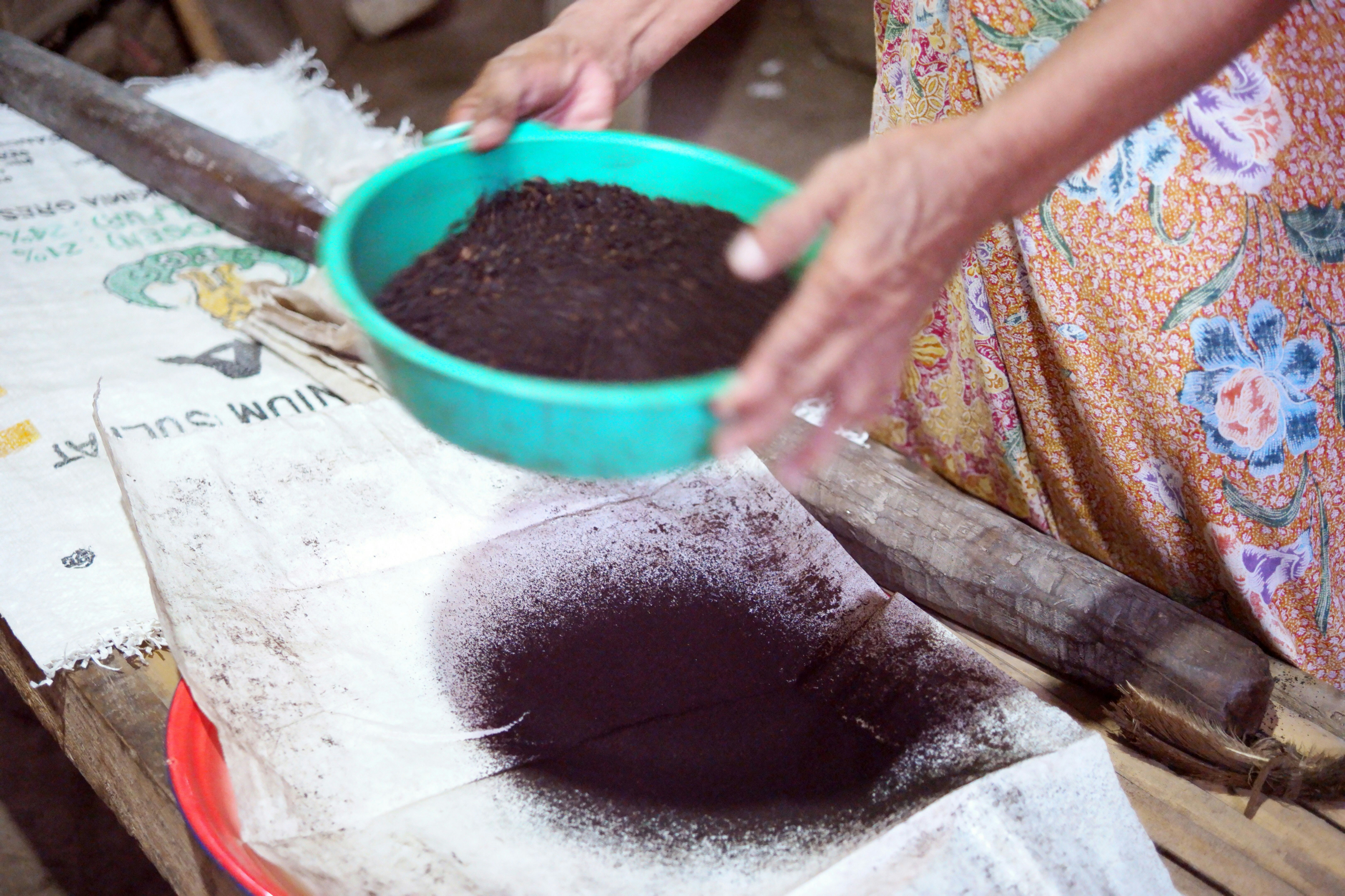 a woman scooping dirt into a blue bowl