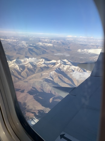 A scenic mountain landscape viewed from a plane flying above the clouds.