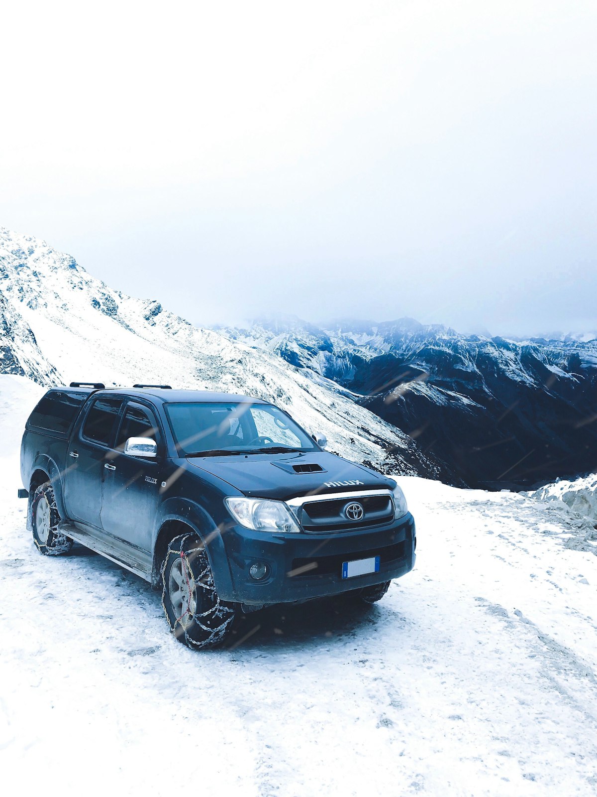 Black Toyota Tacoma pickup truck on snow-capped mountain overlanding trail