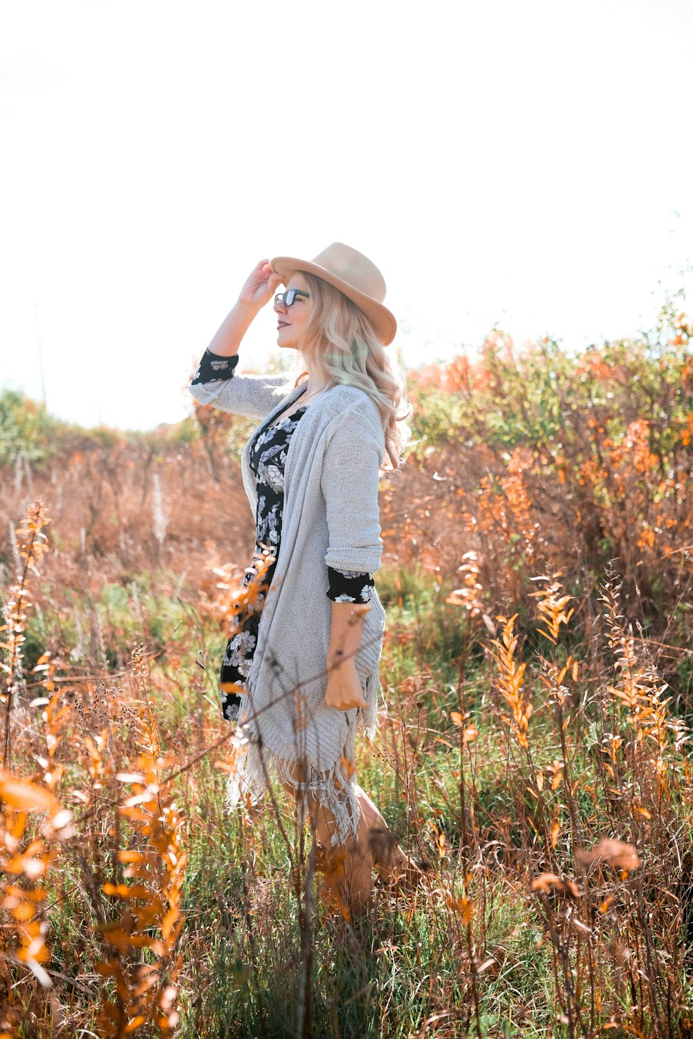 woman in open cardigan standing on grassy field