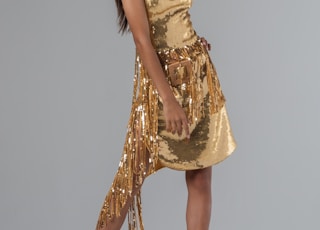 woman wearing gold deep V-neck sleeveless mini dress standing