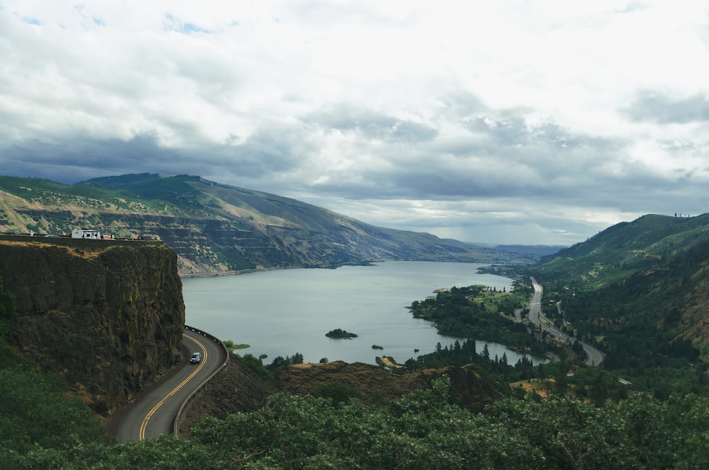 photography of white vehicle on road near lake and mountains