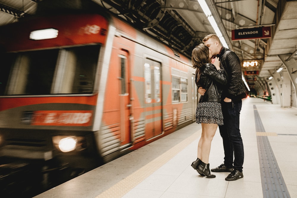 man and woman kissing beside train