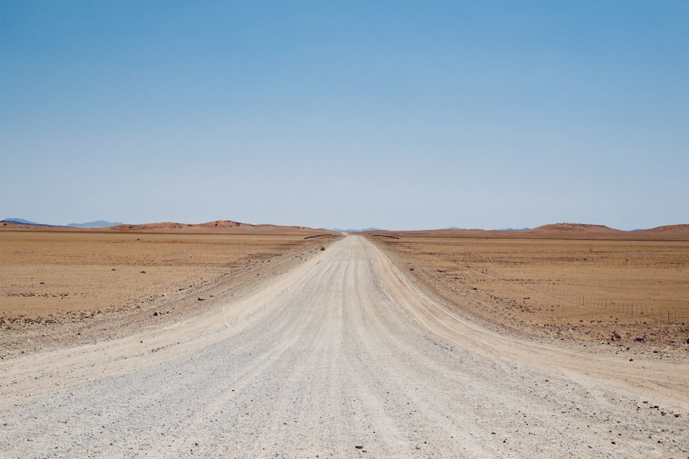 empty dirt road under blue sky