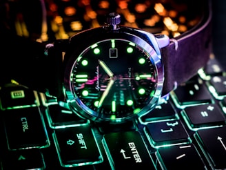 Sleek analog watch with glowing green accents on a dark background