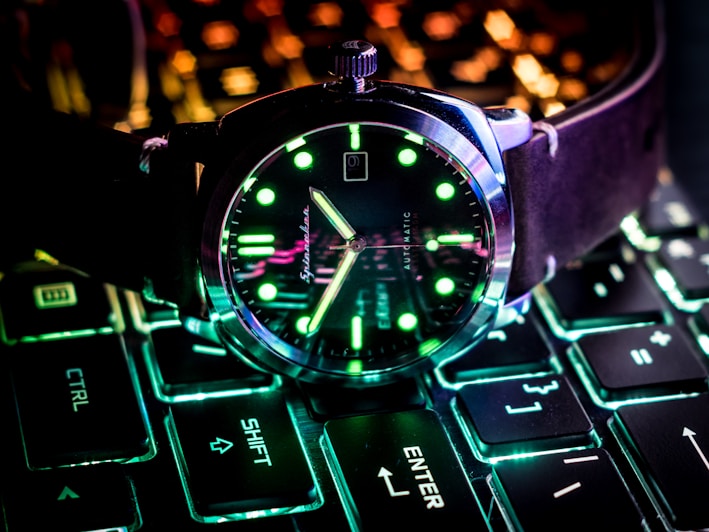 Sleek analog watch with glowing green accents on a dark background