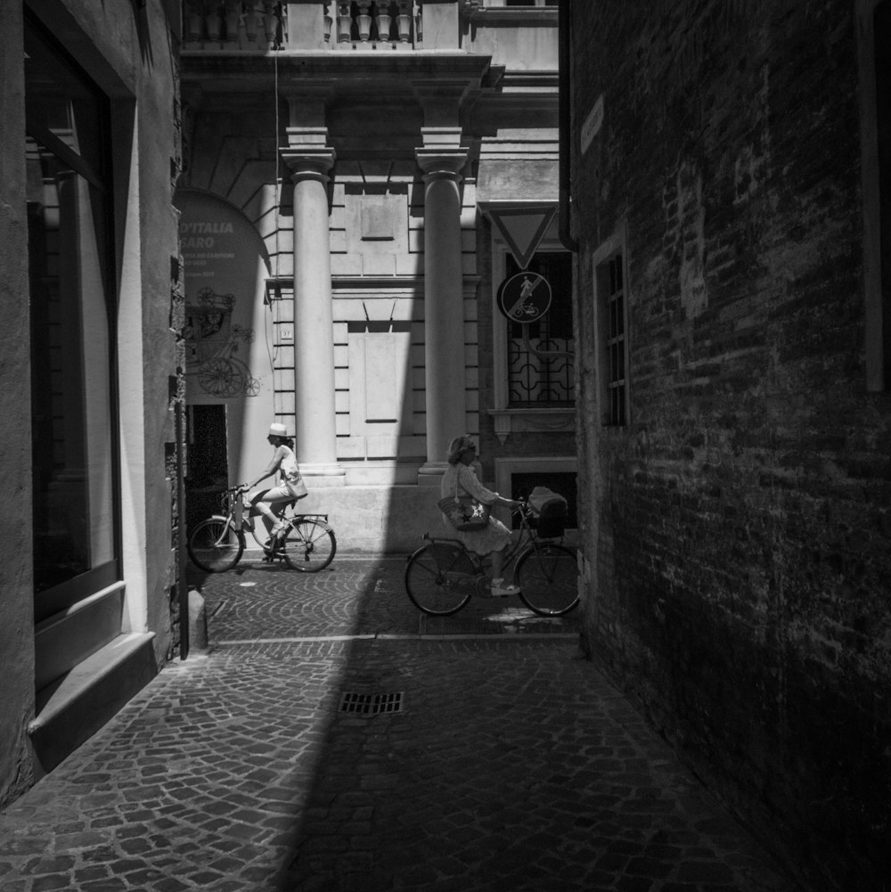 Fotografía en escala de grises de personas en bicicleta durante el día