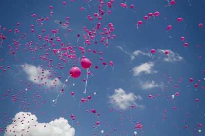 A playful scene of pink balloons floating against a pastel pink sky.