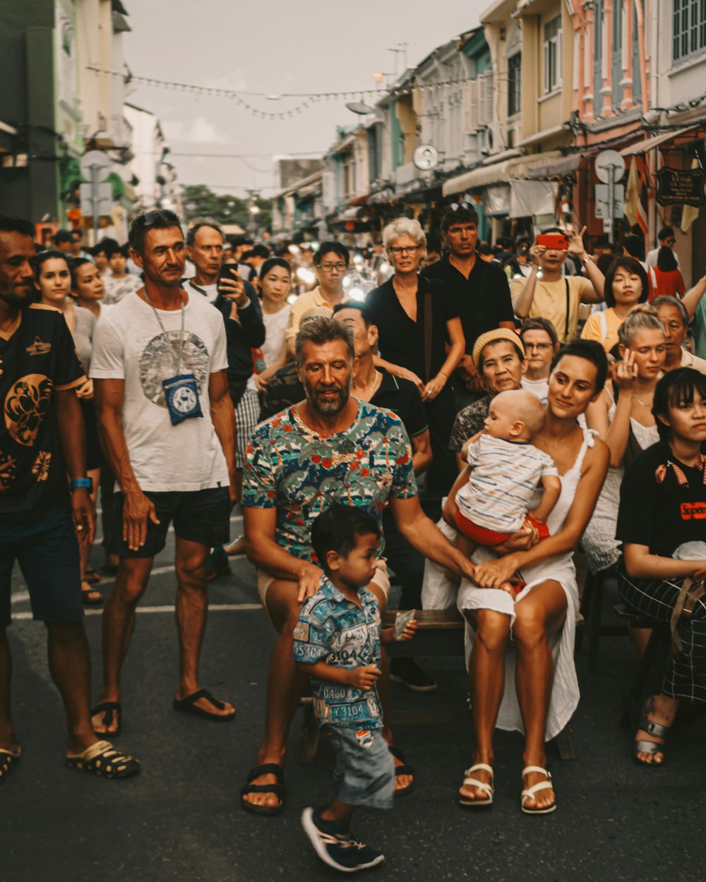 crowd standing and sitting on road during daytime