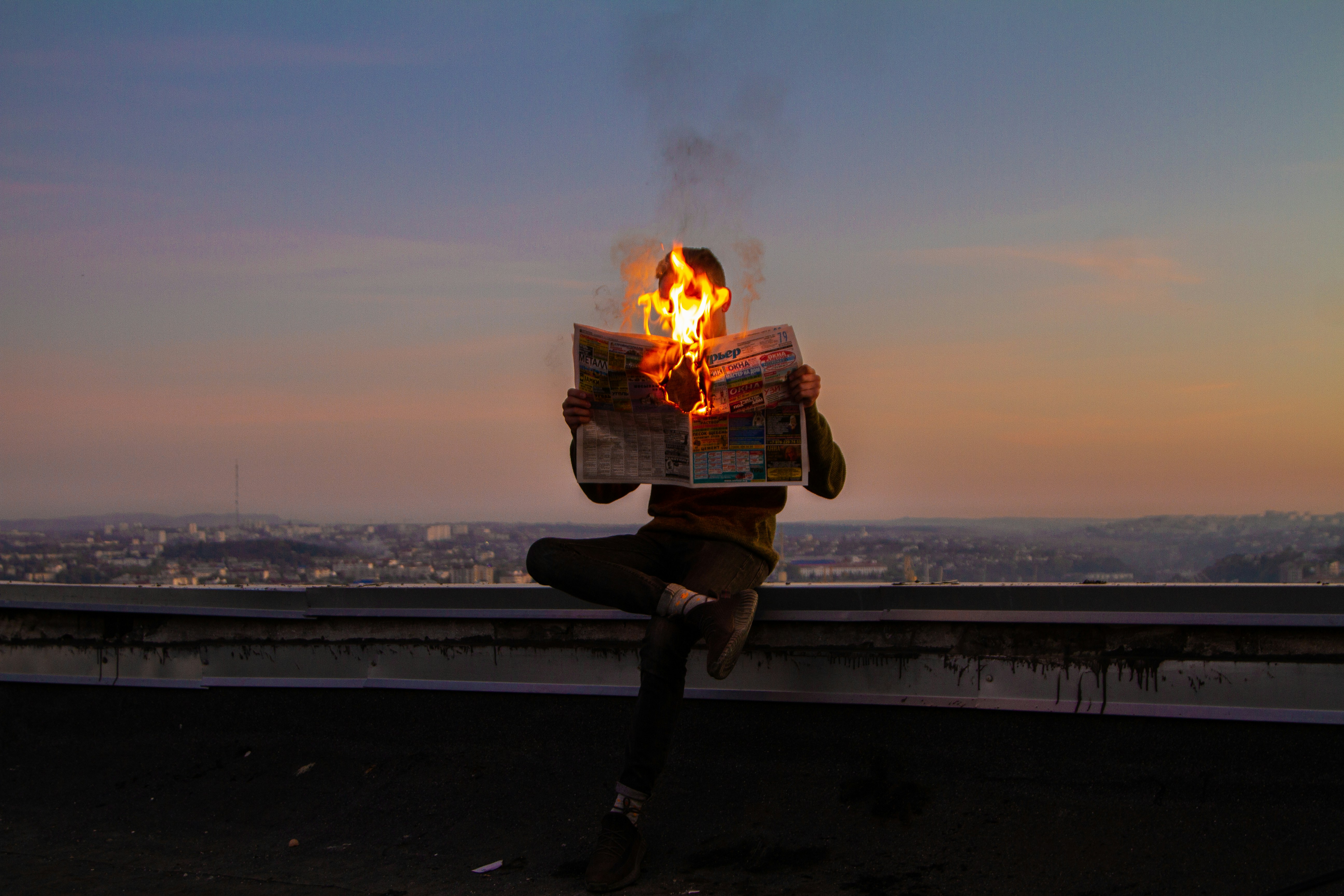 man holding flaming newspaper