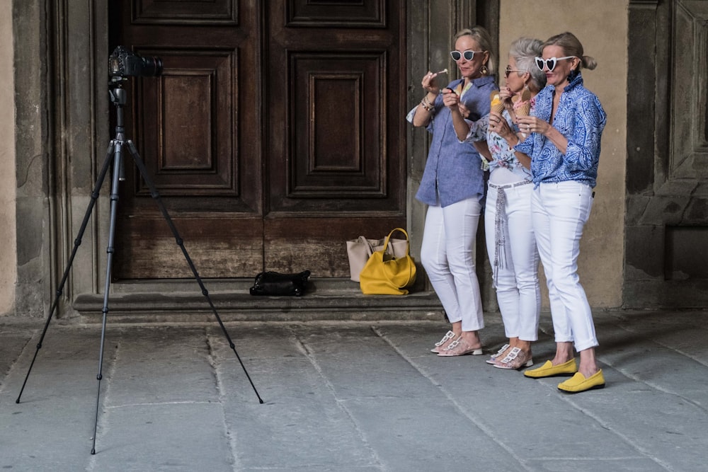 three women standing while holding ice cream beside building