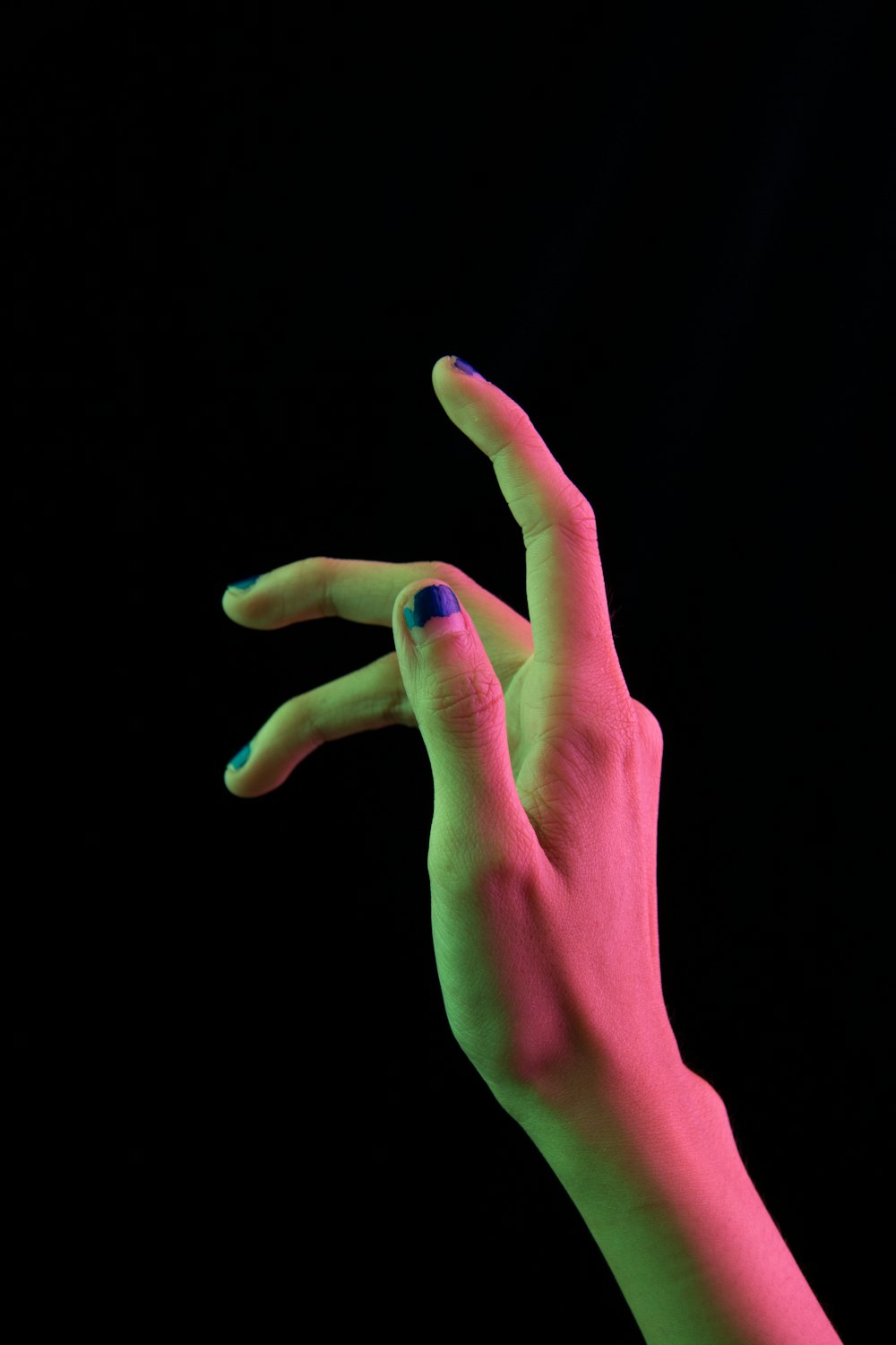 a person's hand with blue and green nail polish