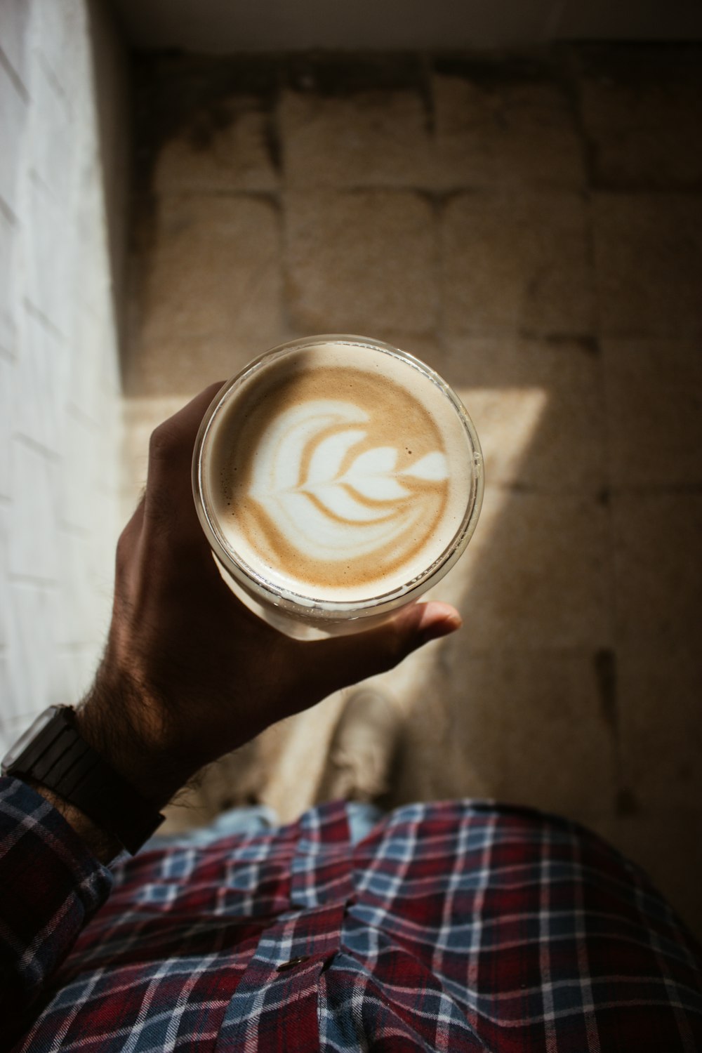 Person, die Trinkglas mit Milchkaffee hält