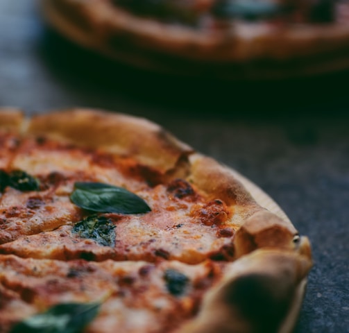 selective focus photography of two pizzas