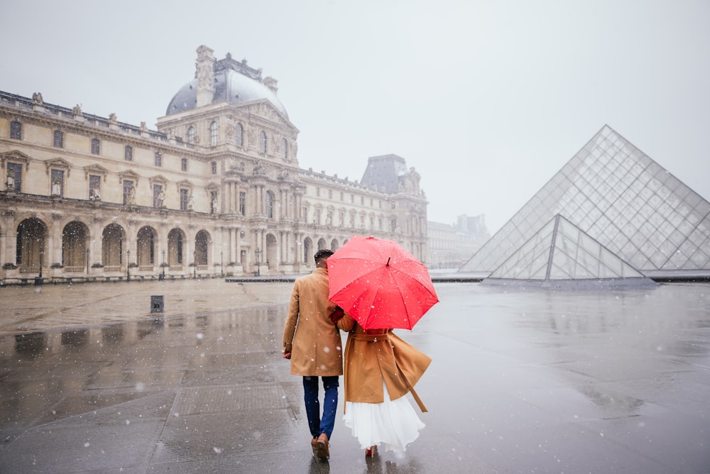 man and woman holding red umbrella