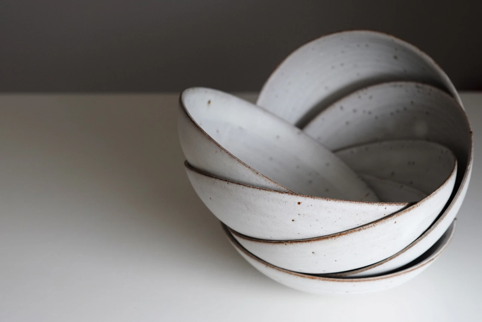 A set of speckled stoneware bowls stacked on a pale surface