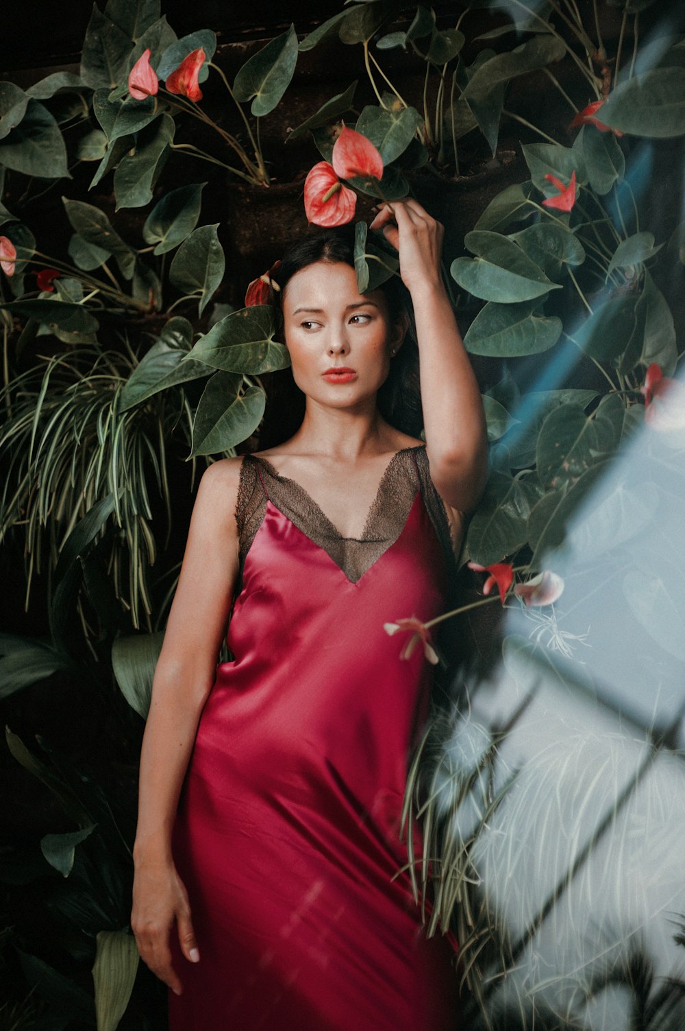 woman wearing red dress standing beside green plant