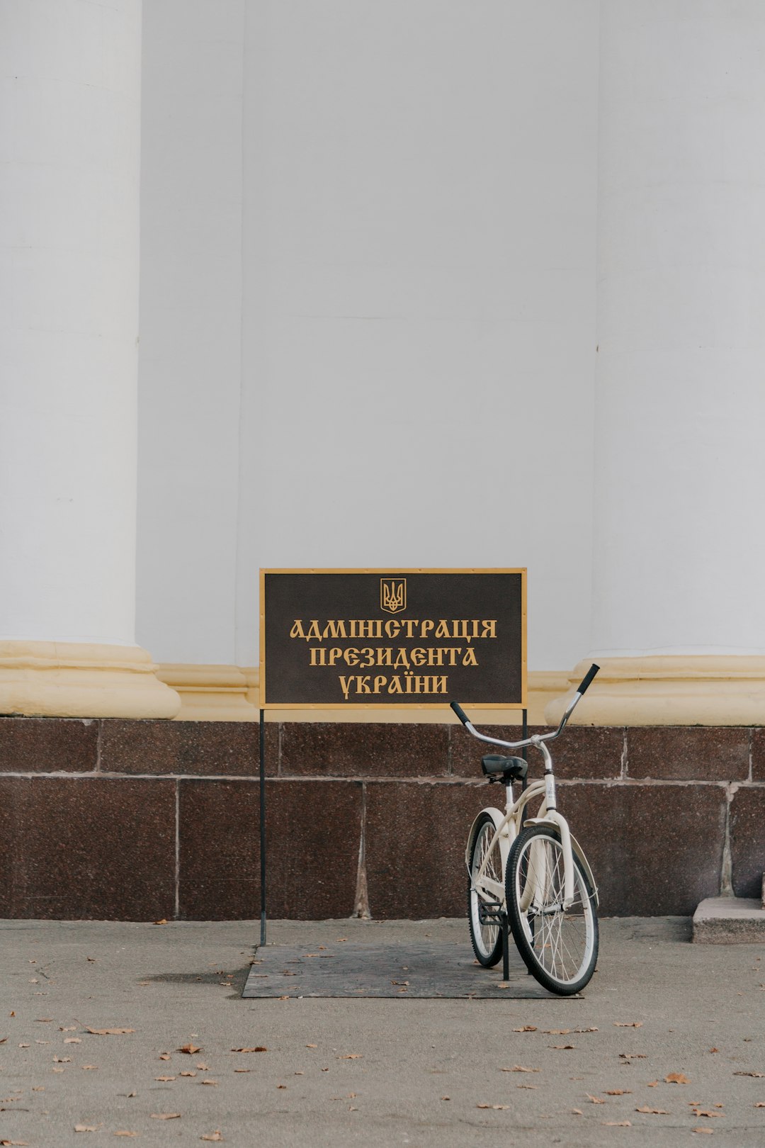 parked white bike beside black and brown sign