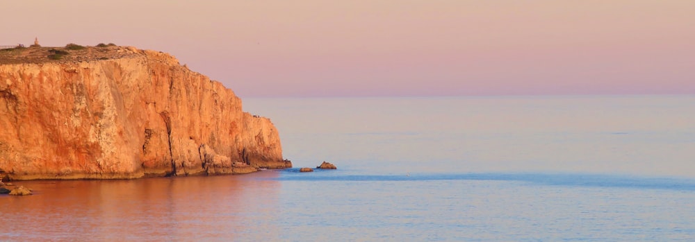 orange rock formation beside body of water during daytime