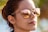 A person wearing reflective sunglasses that show a beach scene with palm trees and a structure in the reflection. The background is slightly blurred, emphasizing the focus on the reflective surface of the sunglasses.