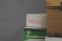 A stack of cardboard boxes, with the top box labeled 'FRAGILE' in red text. Below it, a green box marked 'Sustainable Earth' is visible. Another box, brown with black stripes, is partially in view on the right.