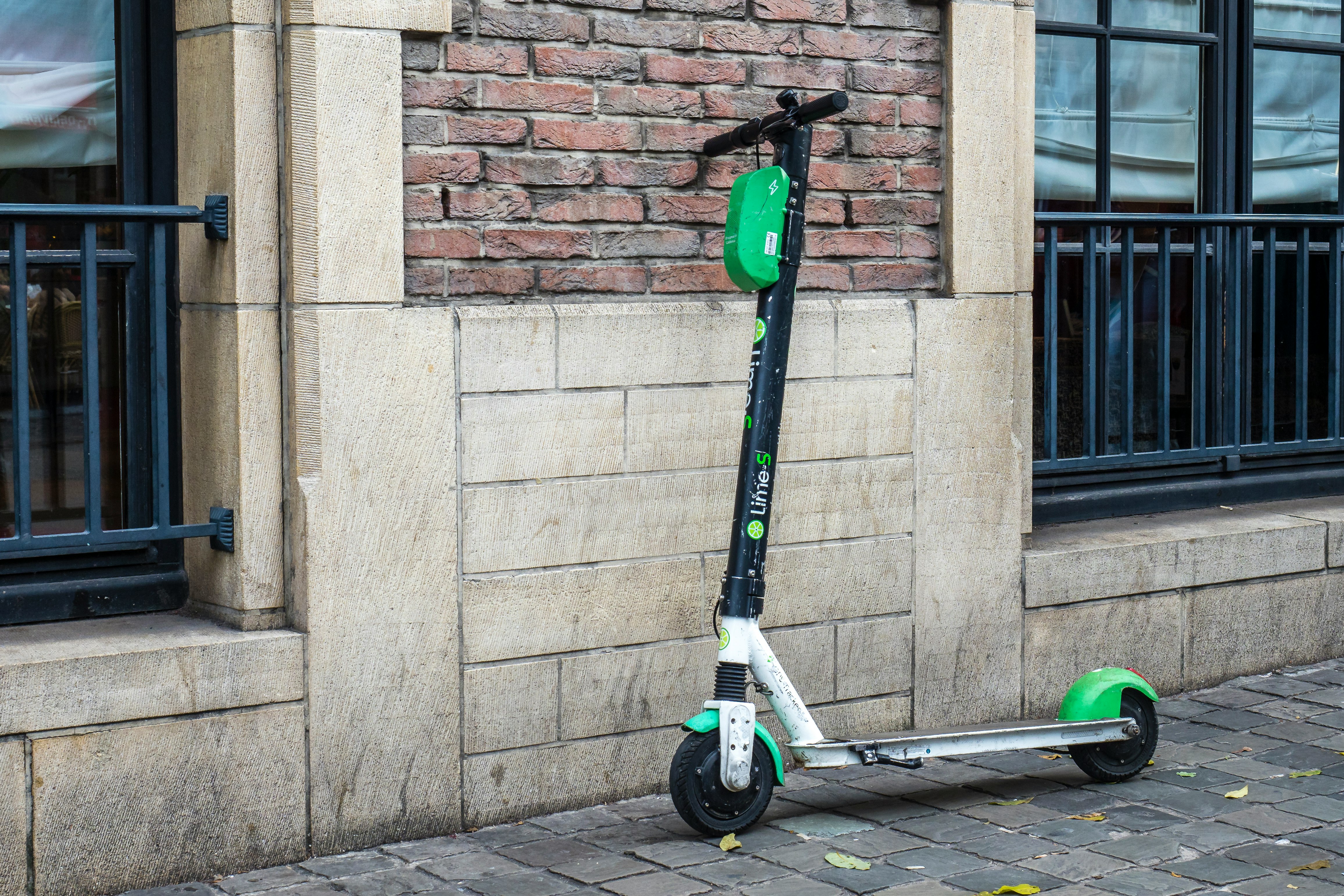 white and green scooter parked beside wall