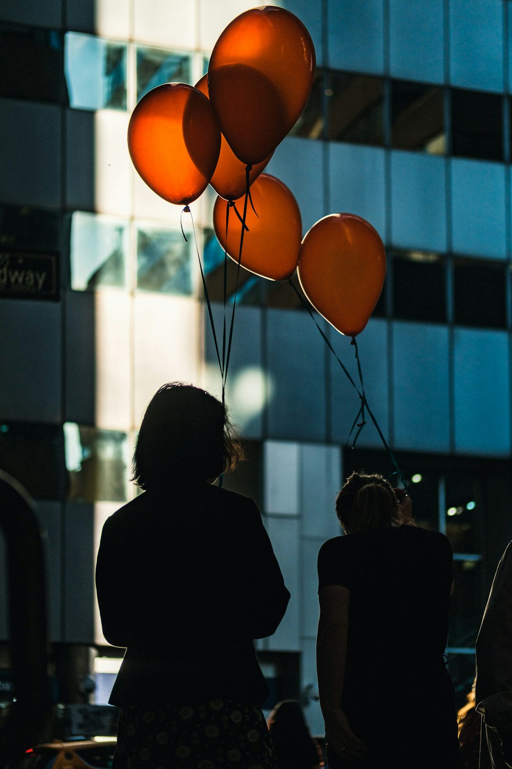 silhouette of women holding balloons
