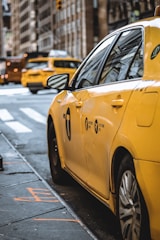 A yellow taxi cab parked on a city street ready for passengers.