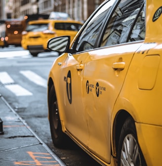 yellow taxi parked beside curb