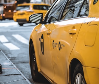 yellow taxi parked beside curb