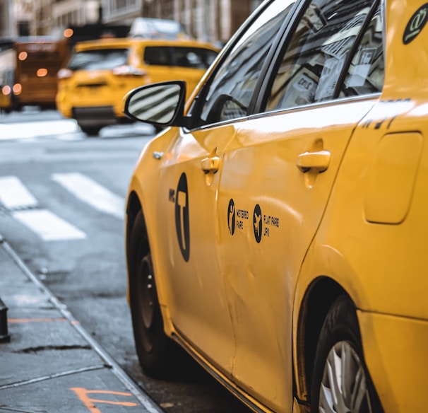 yellow taxi parked beside curb