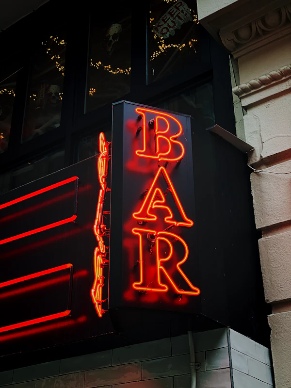 A red bar sign burning against a dark wall