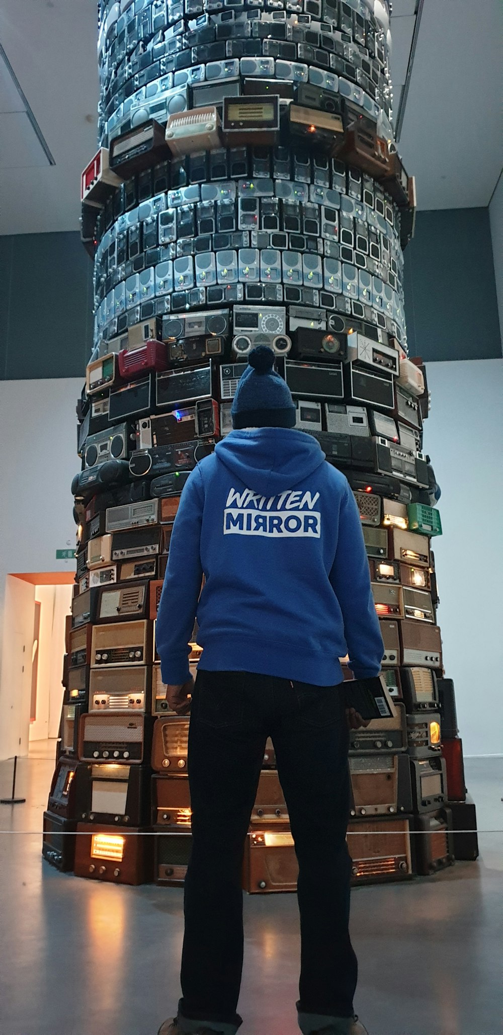person wearing blue hoodie standing in front of tower