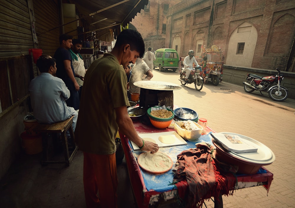 man in green shirt standing near table and road during daytime