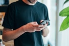 man in black crew-neck top using smartphone